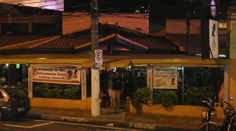 Forneria acolhedora com mesas externas sob cobertura serve pizzas especiais com opções compartilhadas e doces.