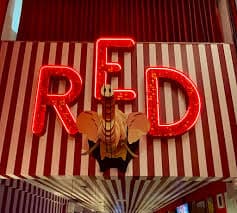 Cantina no estilo fast-food com mesas externas e cervejas serve pizzas diversificadas com opções inesperadas.