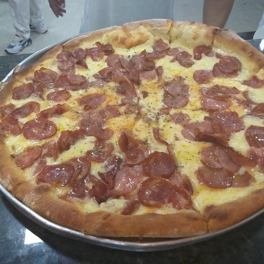 Diversas opções de pizzas, além de bebidas, em espaço rústico, arejado e informal com serviço de entrega.