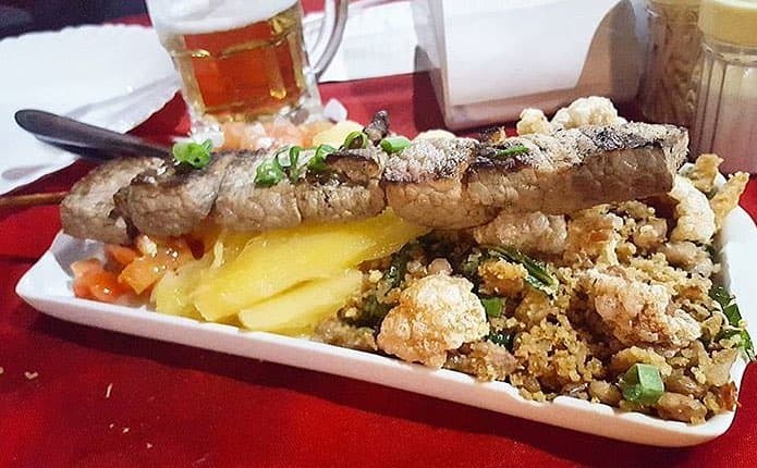 Espacialidades no buffet como feijoada, isca de fígado, peixes, churrasco, bebidas variadas e clima simples.
