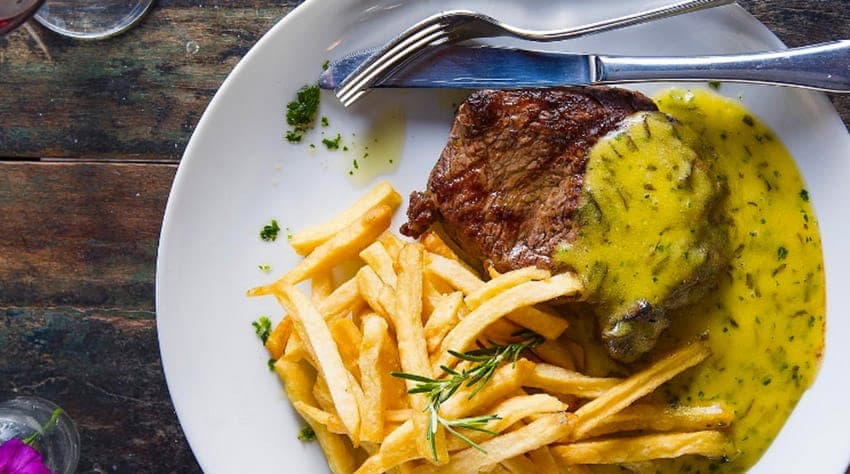 Variedade de pratos brasileiros, como carnes e frutos do mar, em salão amplo e moderno com ambiente externo.