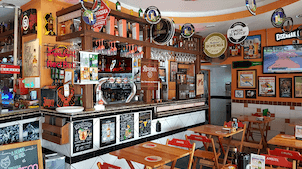 Cervejas e caipirinhas, além de porções fartas, em boteco tradicional com futebol na TV e clima descontraído.