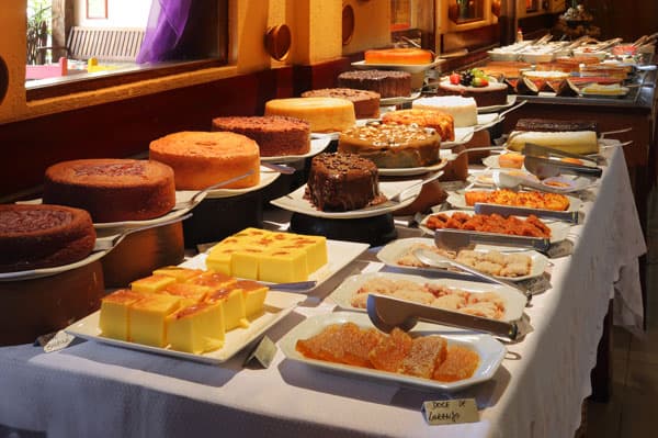 Buffet a quilo com variedade de saladas, pratos quentes regionais, sobremesas, decoração em artesanato local.