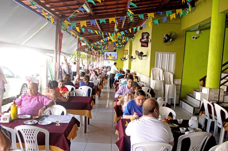 Carne de sol, paneladas e grelhados com fritas, além de garrafas de cervejas, em restaurante e bar rústico.