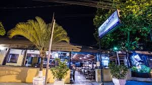 Restaurante descontraído tem menu de porções e pratos populares, em terraço aberto com clima de praia.