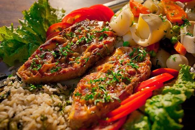 Gastronomia de pescados em receitas regionais de ambiente descontraído com mesas externas em sombreado.