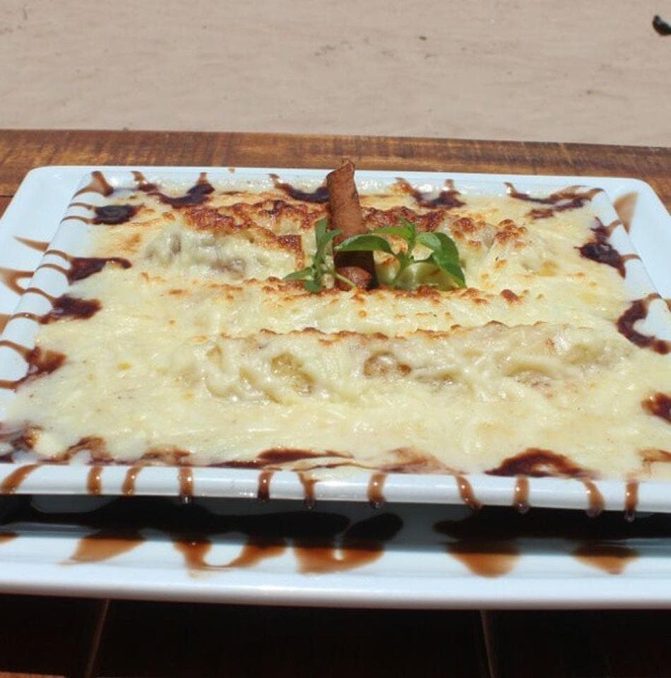 Cervejas, sucos e frutos do mar, em quiosque de praia com canoa de madeira, telhado de palha e música ao vivo.