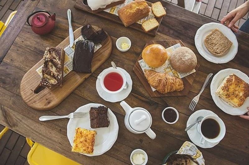 Café da manhã, comidinhas e bebidas quentes, em cafeteria literária sofisticada e intimista, com área externa.