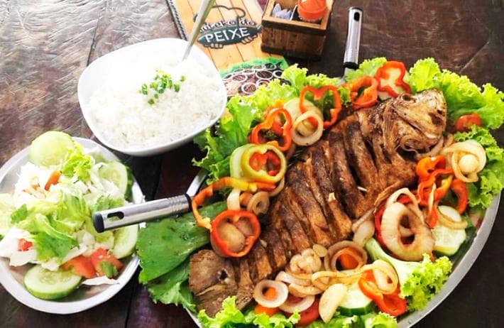 Peixes variados e acompanhamentos, mais cervejas e caipirinhas, em ambiente rústico, descontraído e familiar.